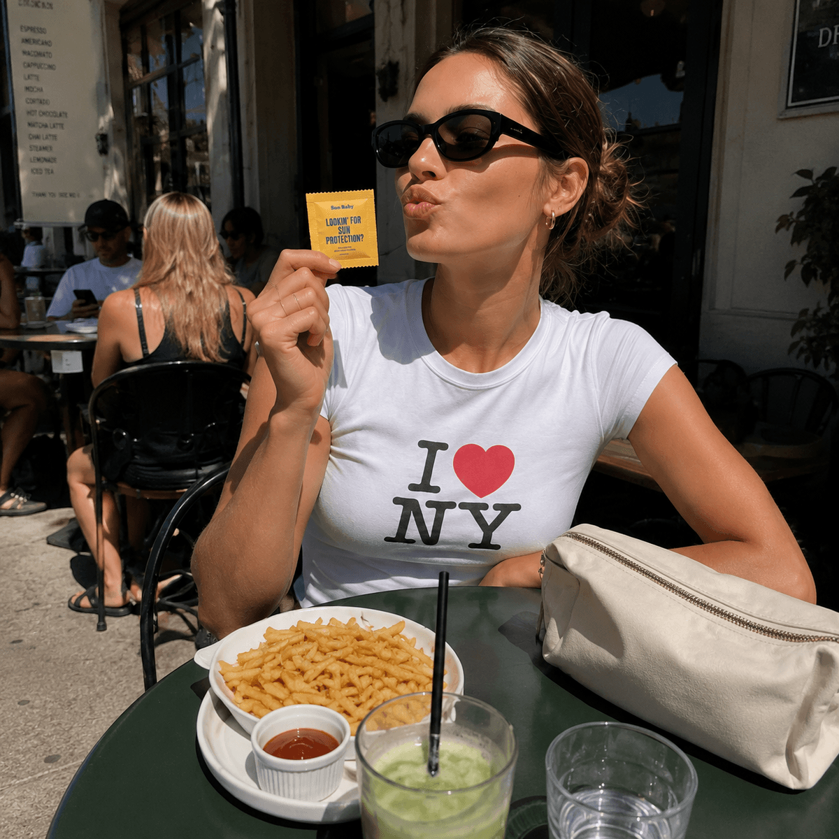 Holding a Sun Baby packet at an outdoor cafe table